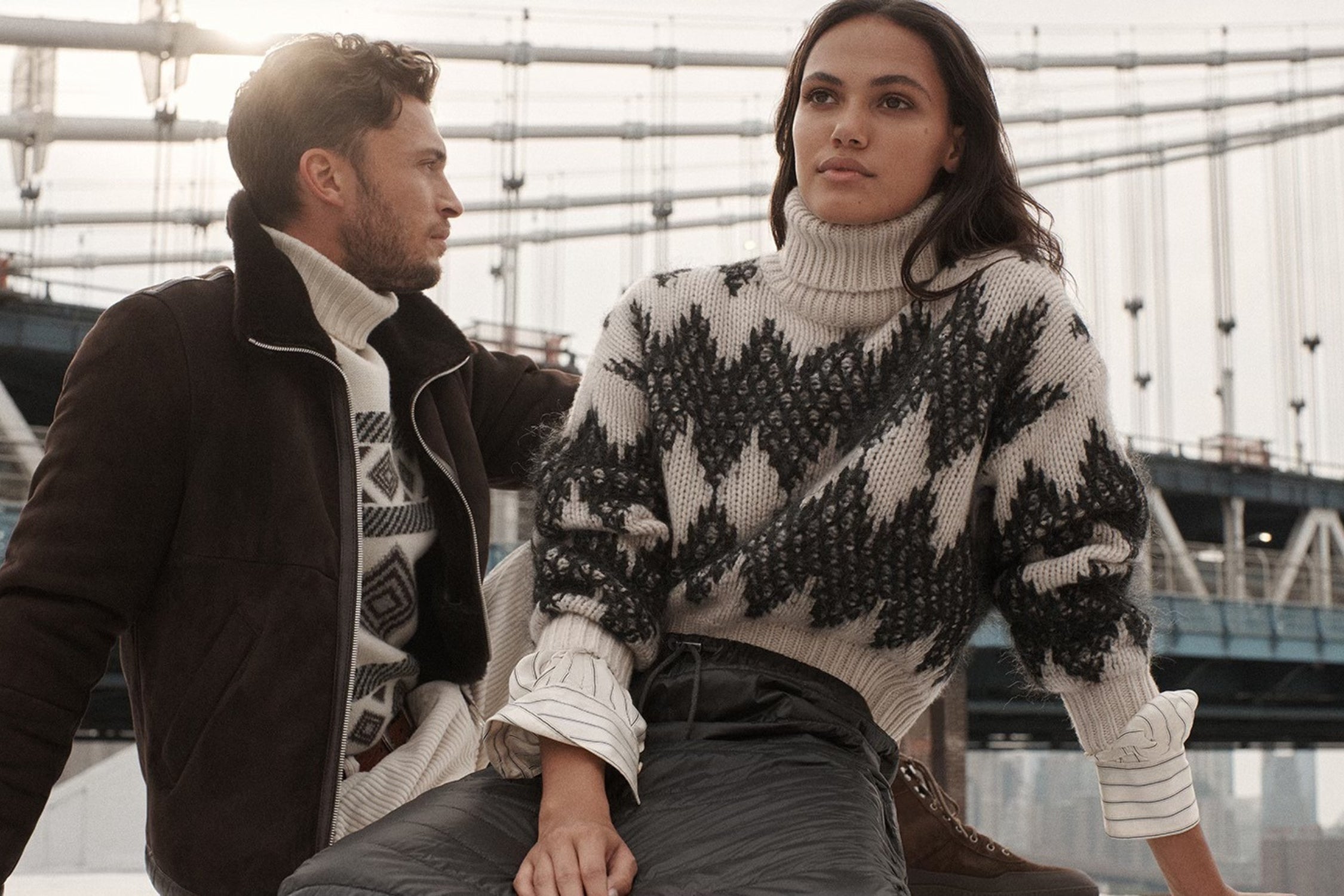 Couple wearing cozy Brunello Cucinelli winter outfits by the bridge.