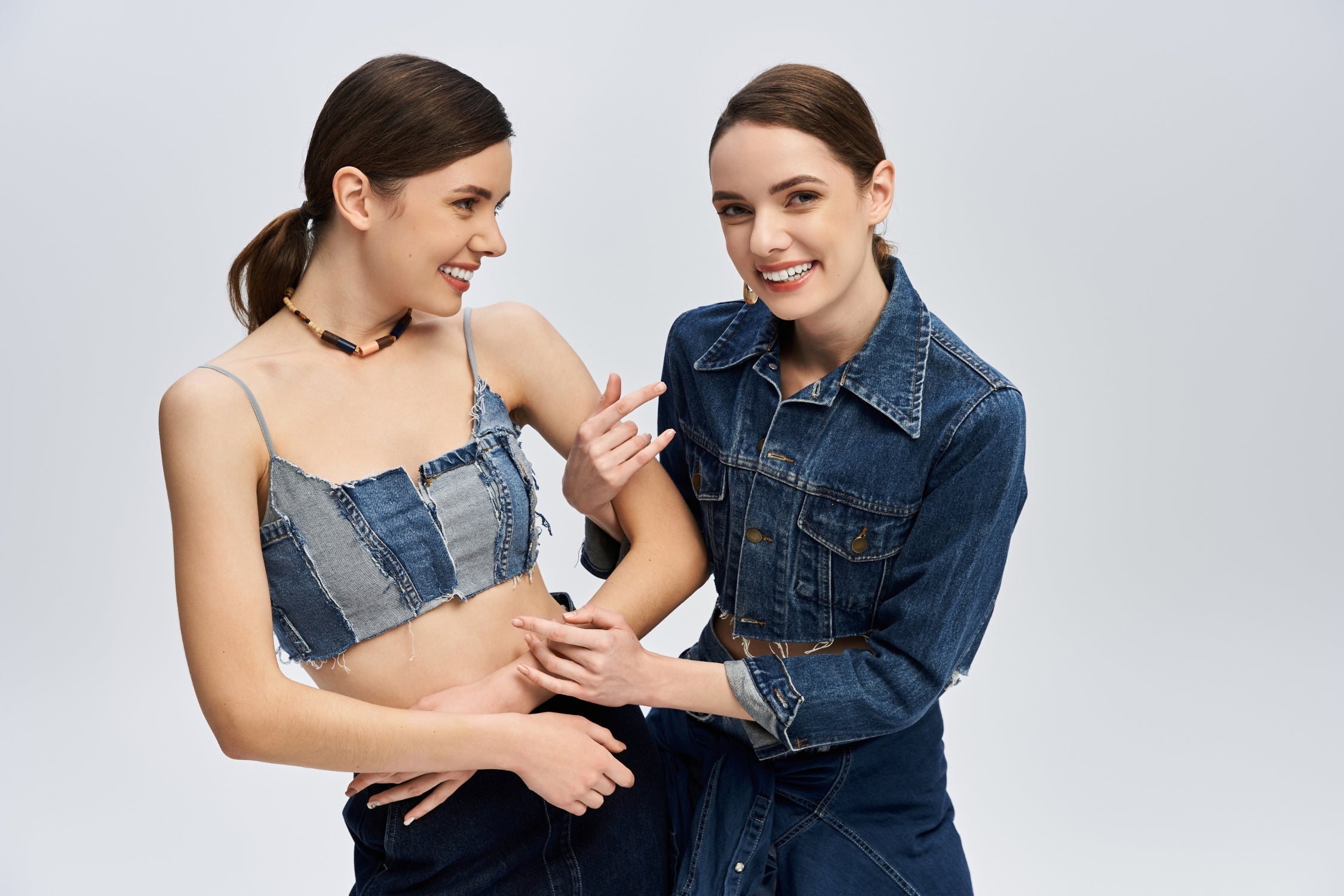 Two women smiling in stylish denim outfits and matching jackets.