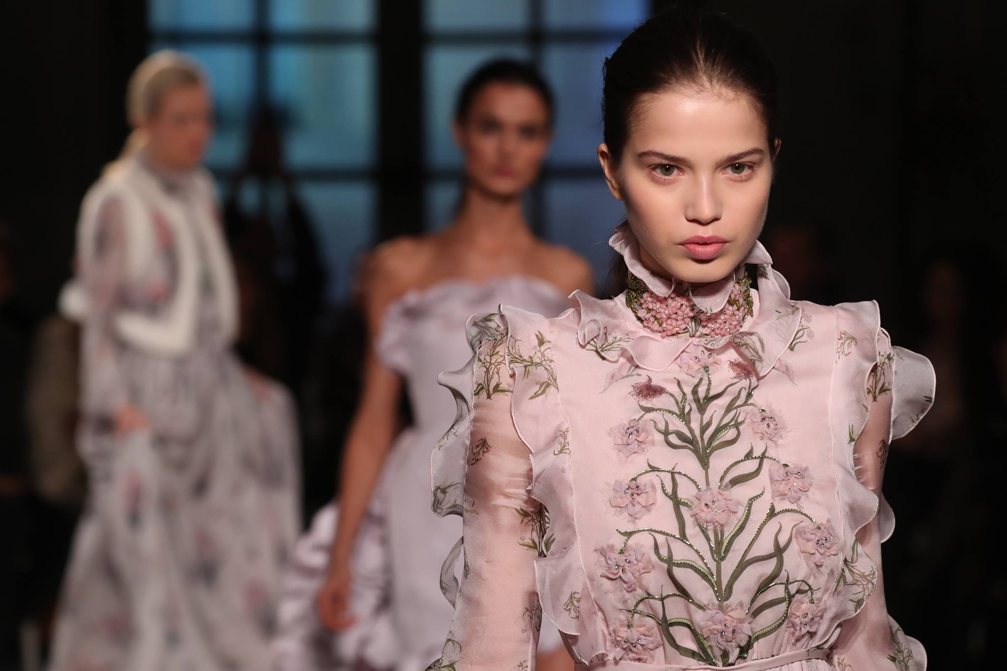 Runway model in embroidered gown showcasing haute couture fashion.