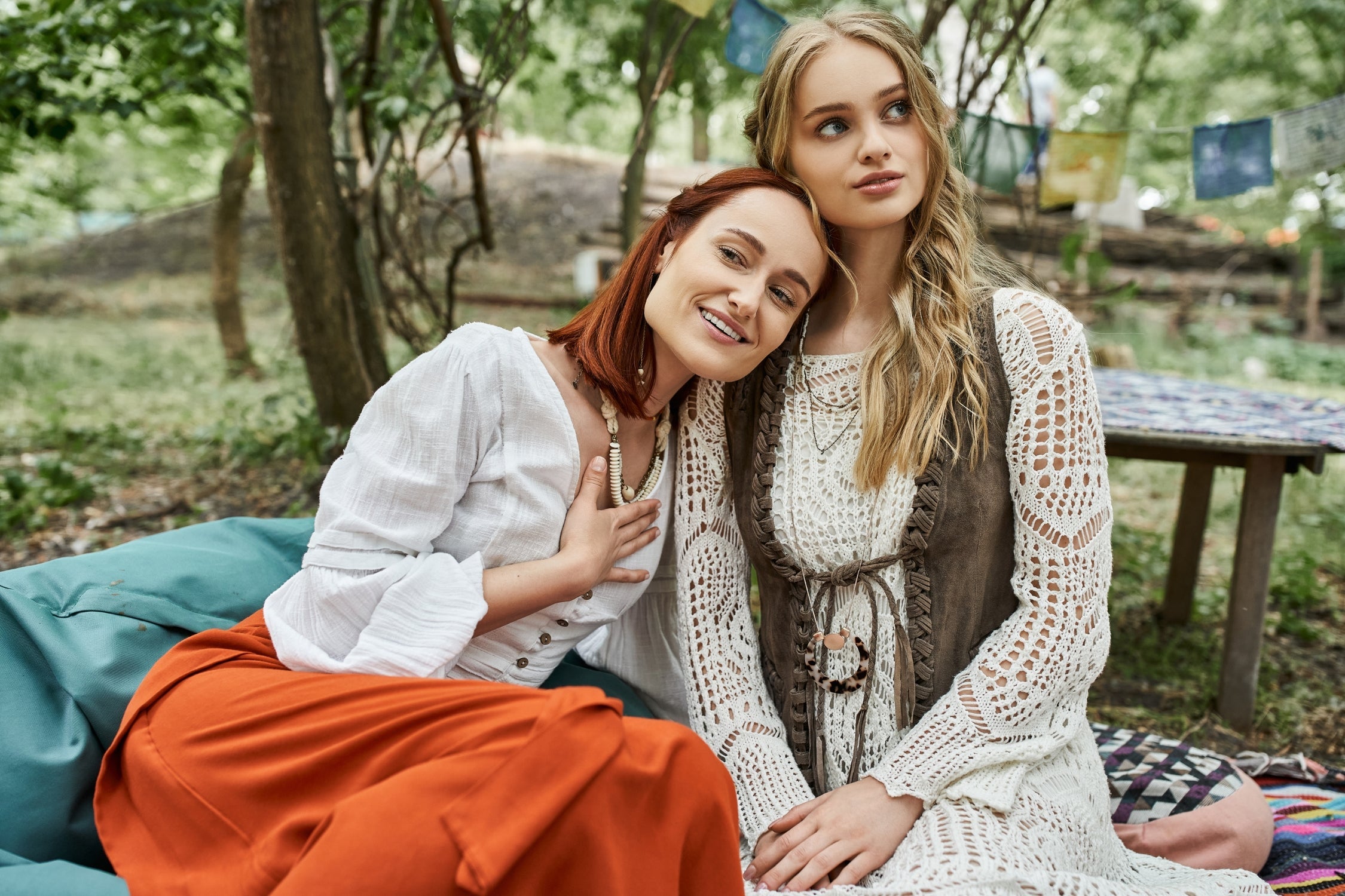 Two women in bohemian-inspired cottagecore outfits relaxing outdoors in earthy tones.
