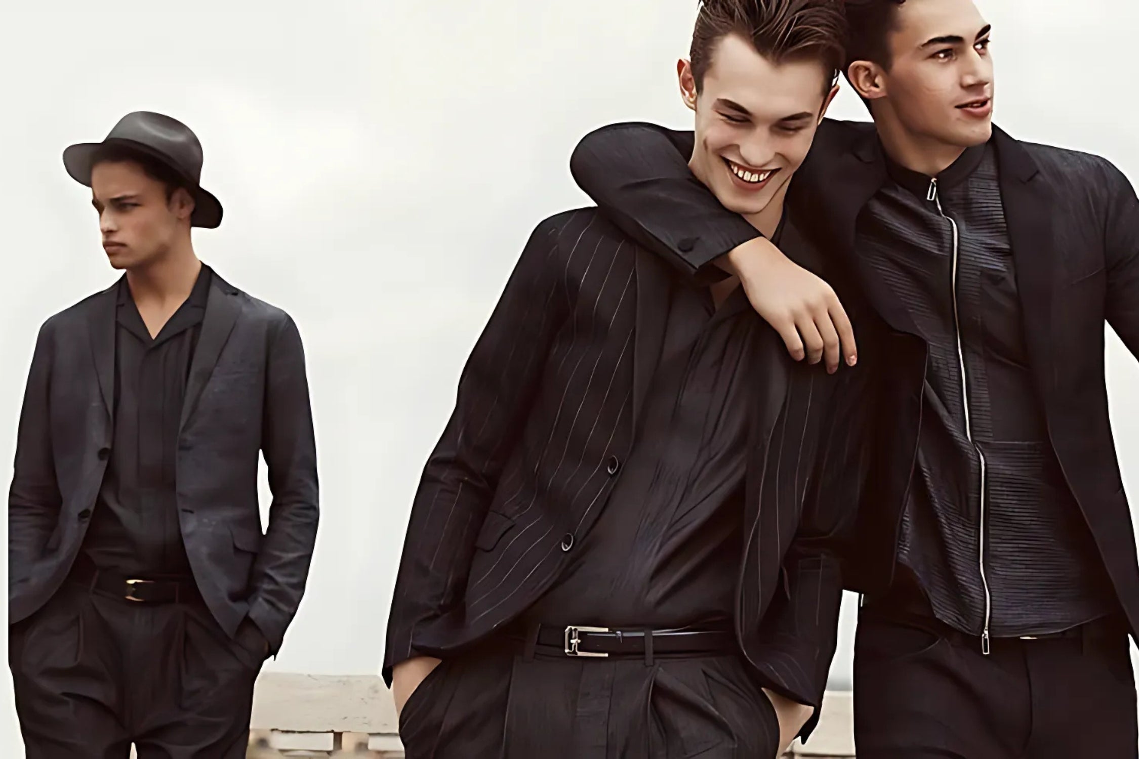 Three stylish young men wearing modern black suits, exuding sophistication and camaraderie.
