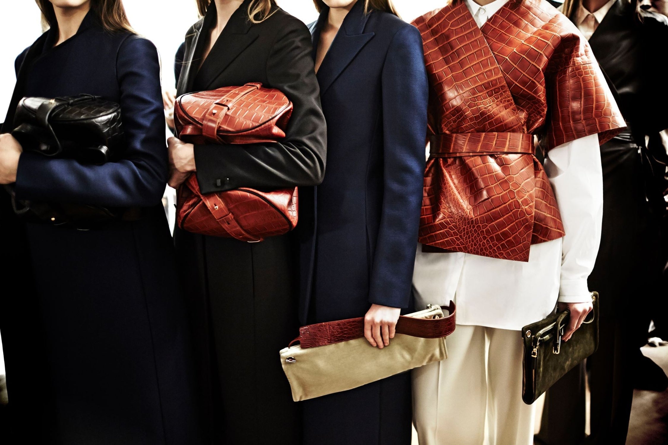 Models dressed in tailored coats and tops showcase oversized clutches and textured pieces from The Row.