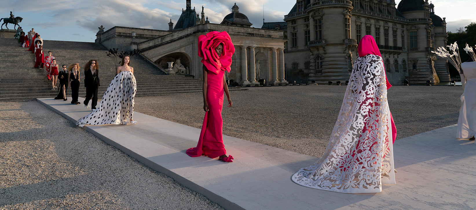 Runway models in dramatic couture gowns at a historic château, showcasing Italian Fashion Houses’ bold elegance and craftsmanship.