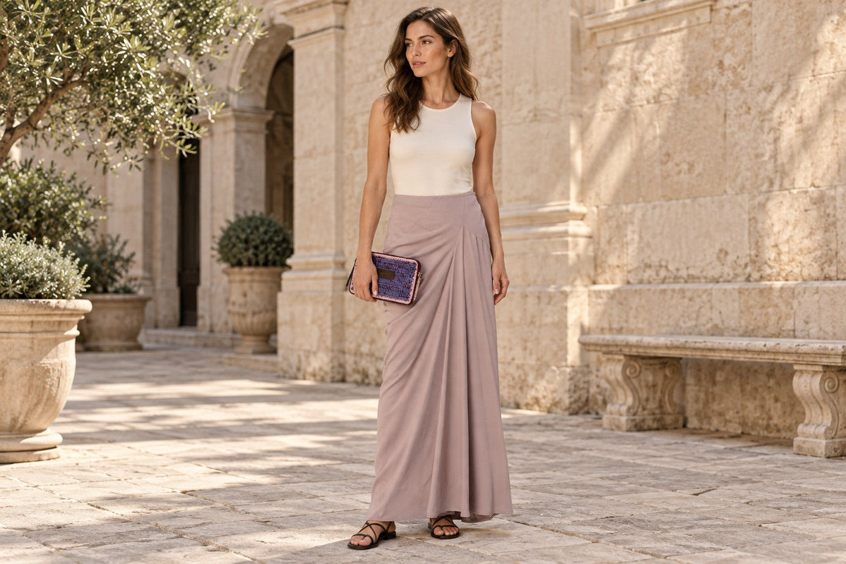 Editorial styling illustration of a woman in a dusty pink Dries Van Noten draped skirt holding a Marni woven camera bag