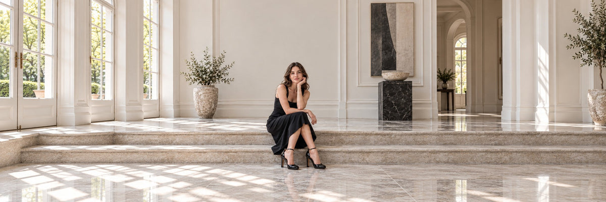 Editorial styling illustration of a woman wearing black patent Valentino Hi Dolly ankle-strap pumps with a black dress.