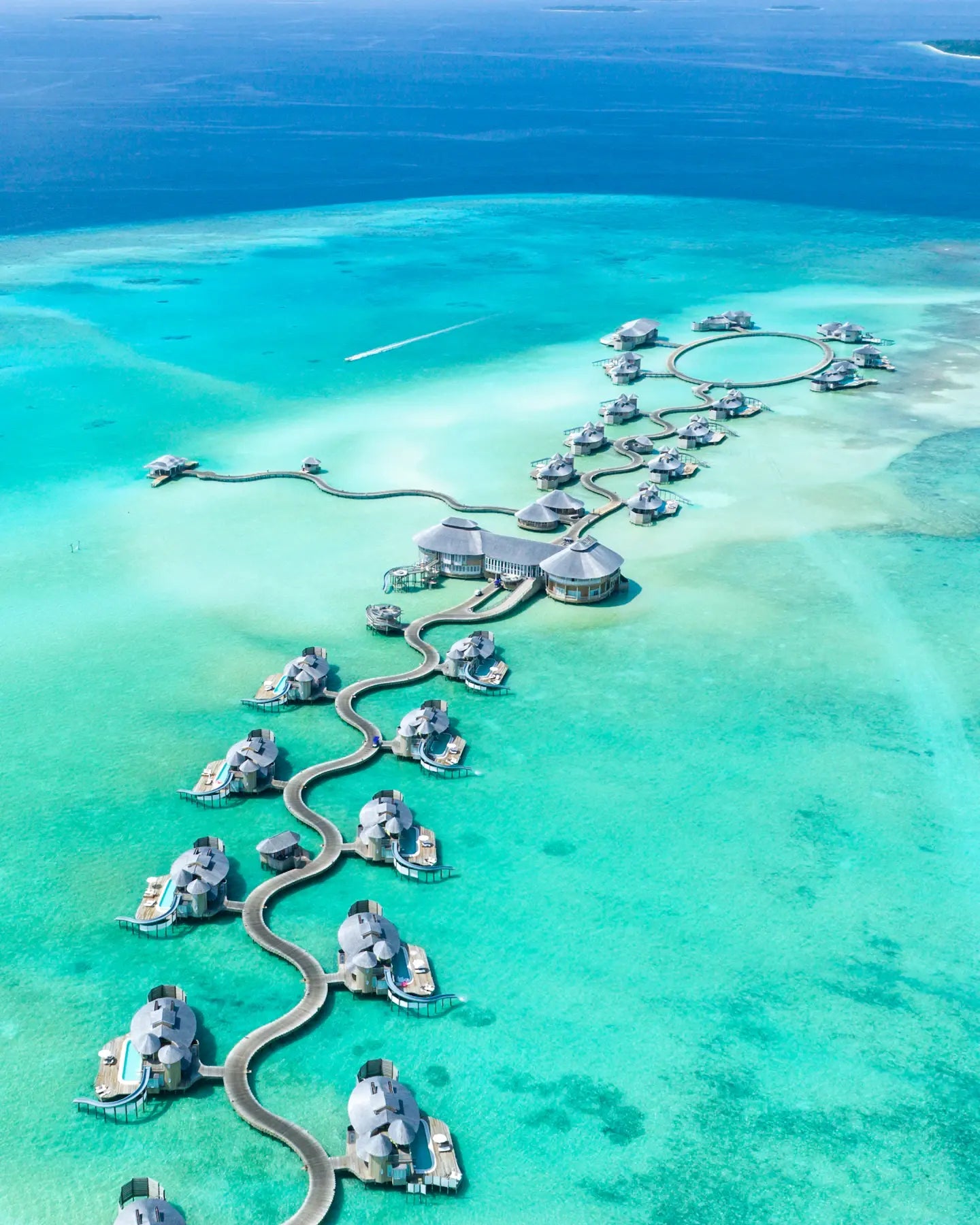 Overwater villas and a winding walkway in a turquoise Noonu Atoll lagoon, Maldives