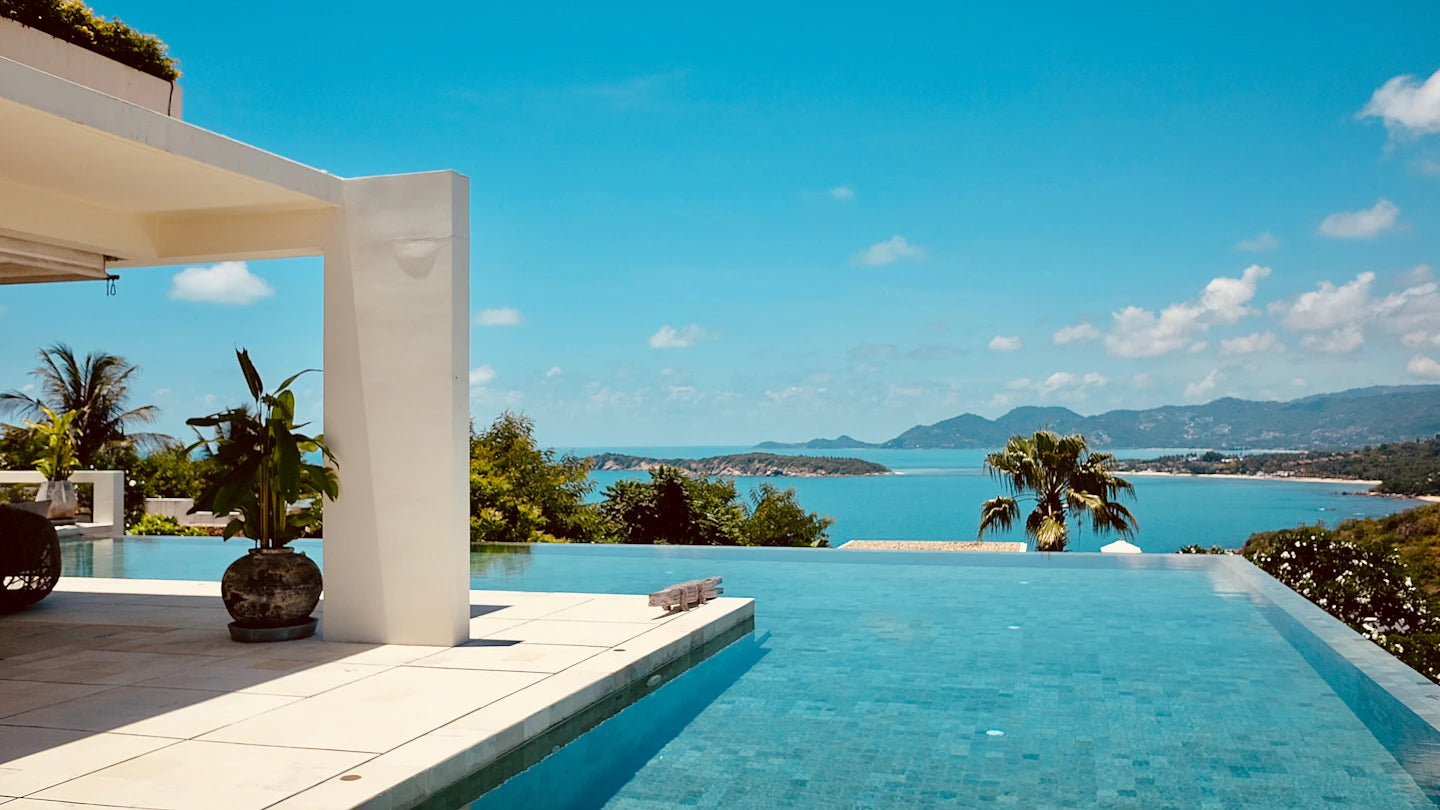 White terrace architecture beside an infinity pool overlooking a blue bay